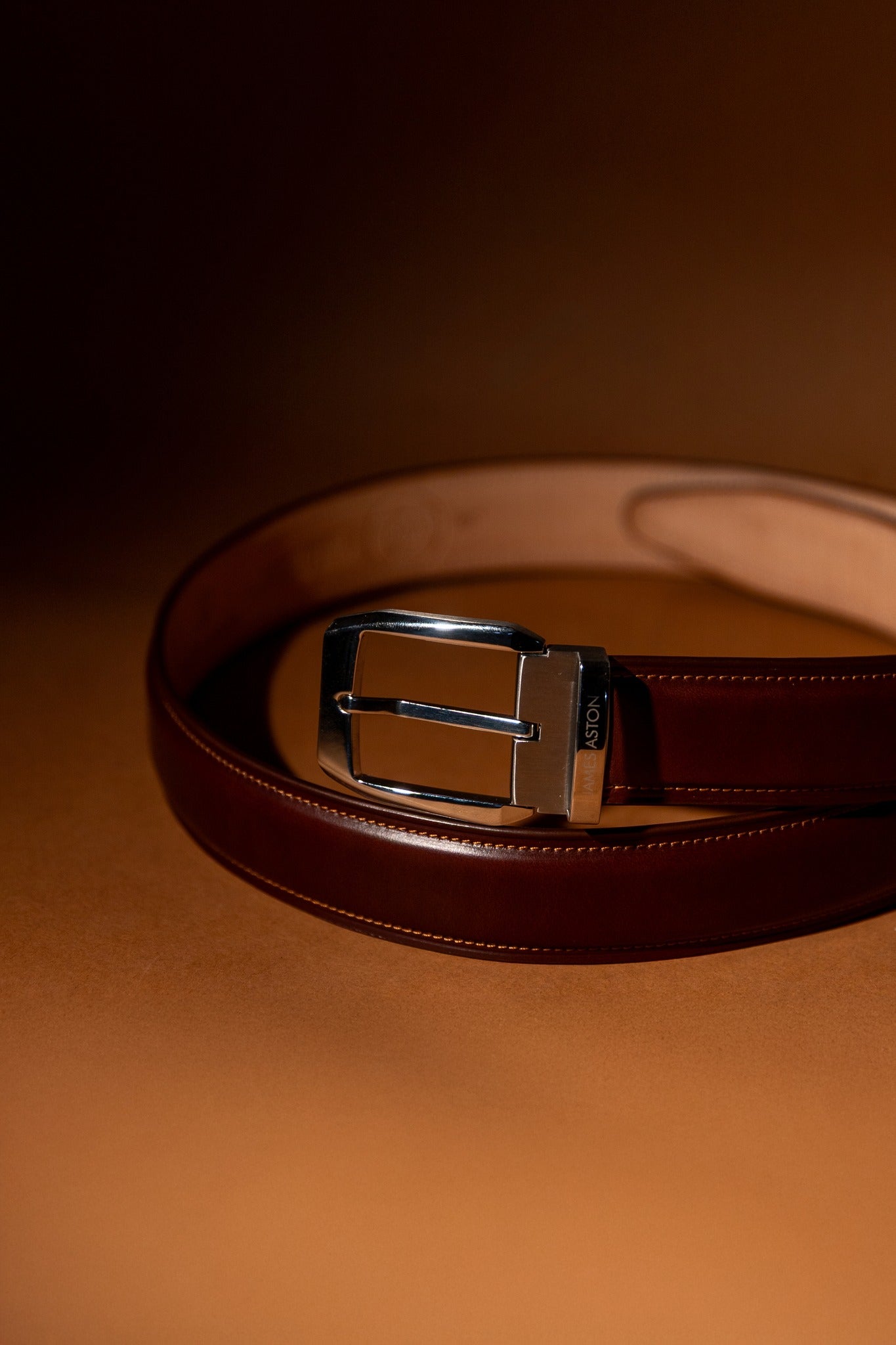 The Cosimo oak brown Italian Bridle leather belt at rest, showing the palladium buckle and tapered frame