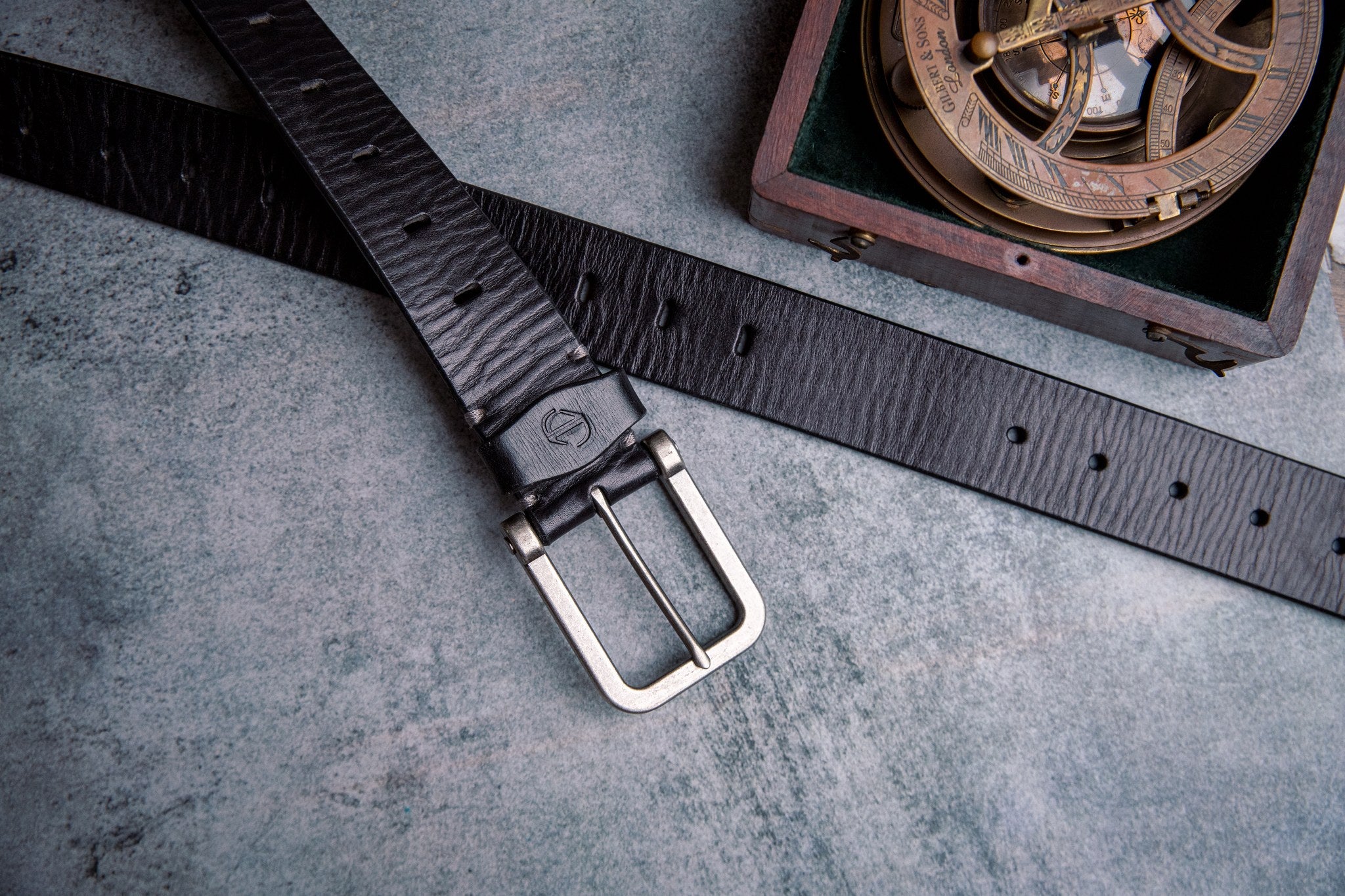 The Alarico belt in black milled leather shown at full length, with dull nickel buckle