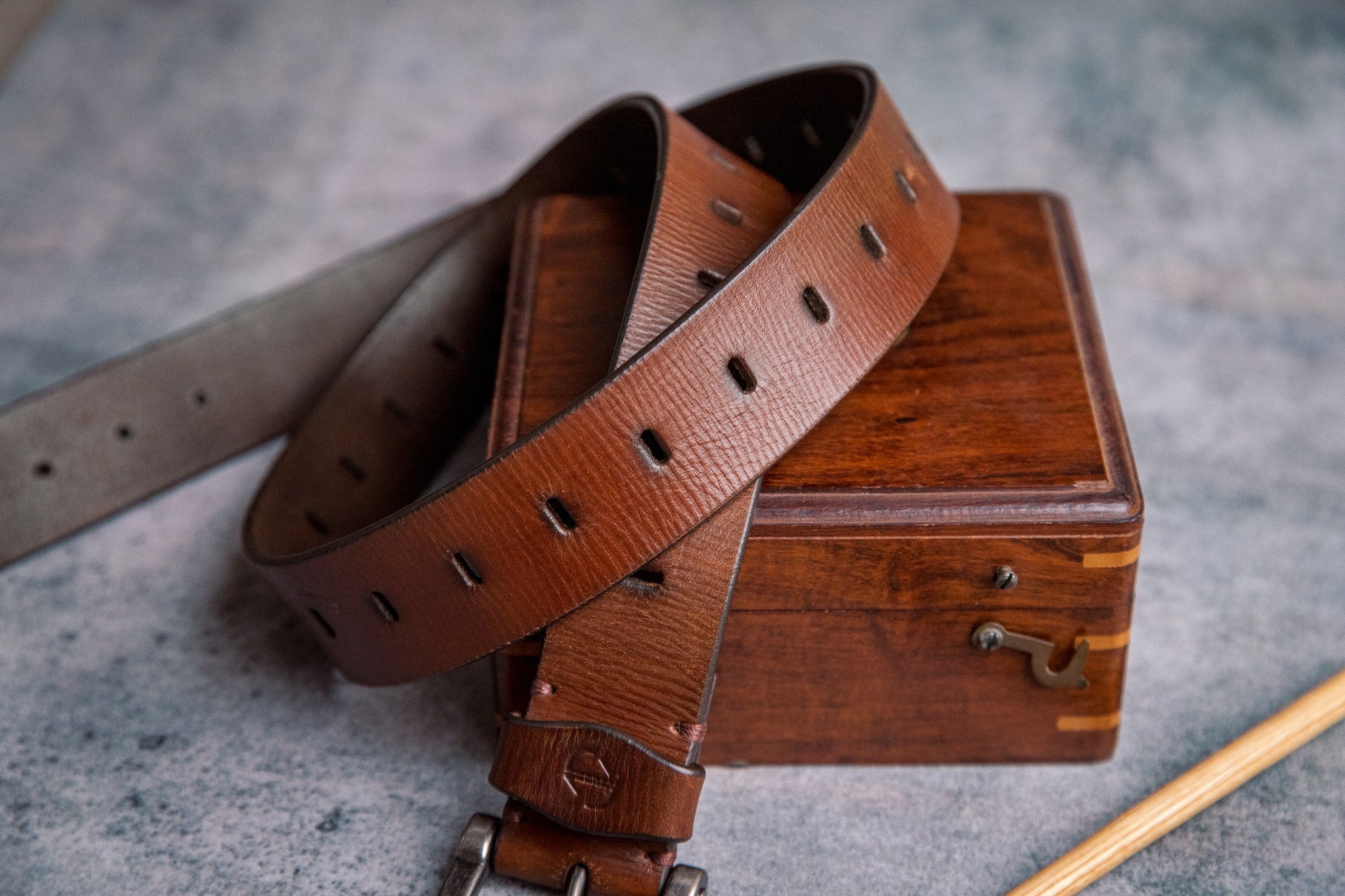 The Alarico belt in cognac milled leather shown at full length, with dull nickel buckle
