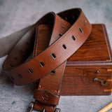 The Alarico belt in cognac milled leather shown at full length, with dull nickel buckle