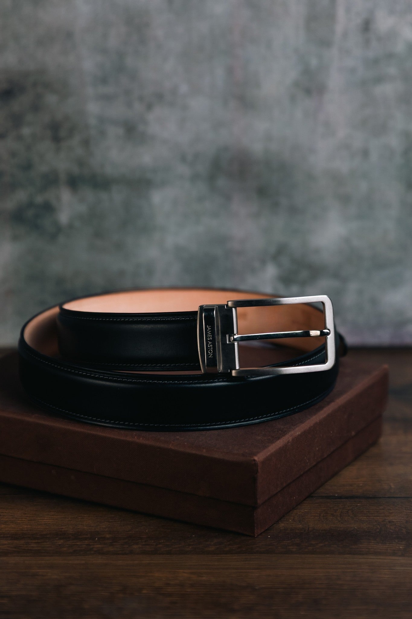 The Cesare Black Italian Bridle leather belt resting on its presentation box, by James Aston