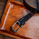 The Damian belt in black milled leather shown at full length, with dull nickel buckle