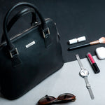 The Executive Handbag in black, carried close.