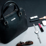 The Executive Handbag in black, carried close.