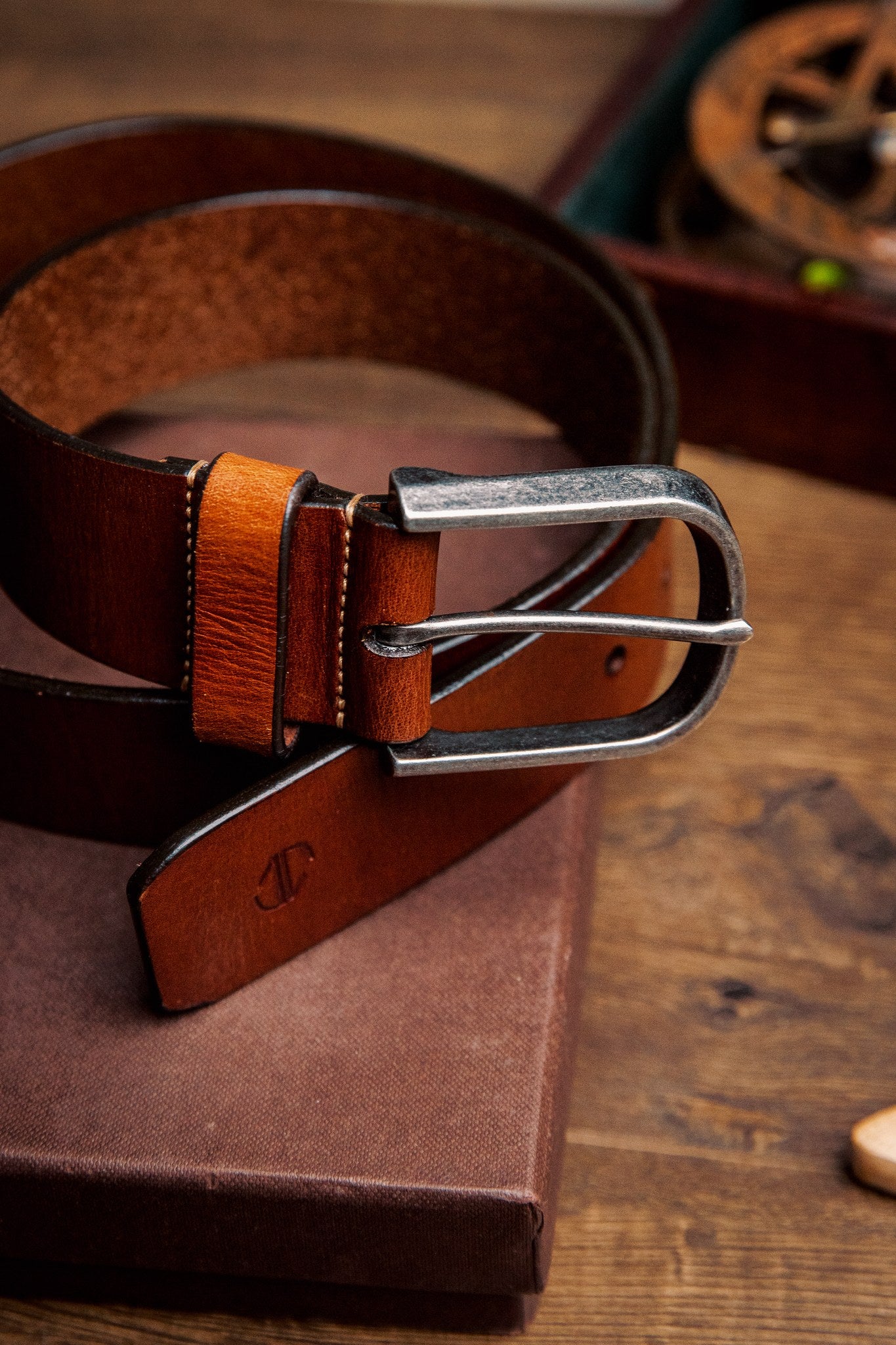 Close view of the silver finish buckle and hand-sewn buckle points on the Pedro belt in cognac