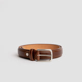 The Ramon cognac dress belt composed on warm wood, by James Aston